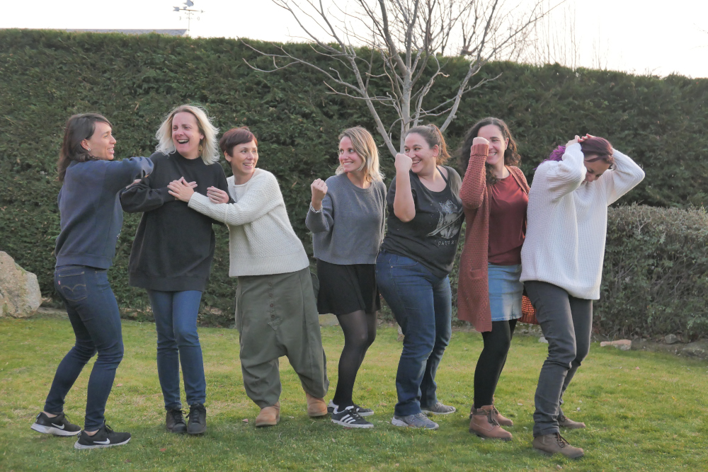 Foto de 7 mujeres kaleiders doblando el brazo y haciendo gestos mostrando poder con fondo de paisajes de montañas