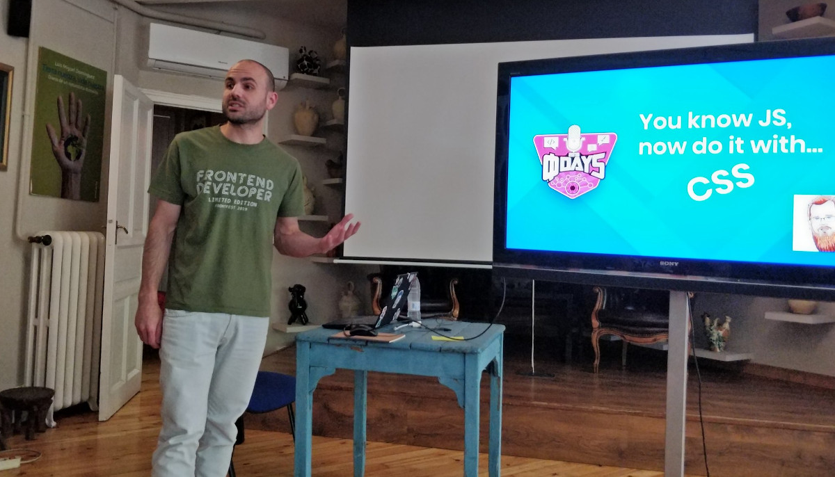 Samuel speaking in front a large screen in a conference room